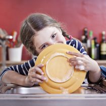 Germany, North Rhine Westphalia, Cologne, Girl washing plates in kitchen sink, close up